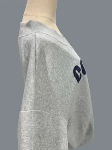 Vista lateral detallada de una sudadera gris con cuello en V y un corte muy holgado