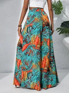 Detailed view of vibrant tropical palm leaf print on high-waisted flowy wide-leg pants.