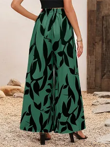 Détail du pantalon large en mousseline verte avec un imprimé de feuilles tropicales noires.