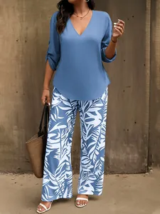 Ganzkörperansicht einer Frau in einem blauen Oberteil und einer weiten Blumenhose