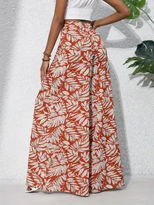 Full-length back view of women's stylish tropical leaf print wide-leg trousers in brick red
