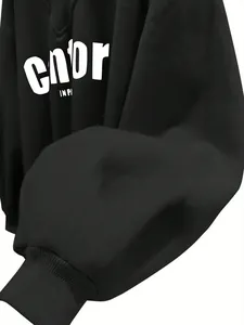 Primer plano de sudadera negra oversize con cuello en V, puño elástico y detalle impreso