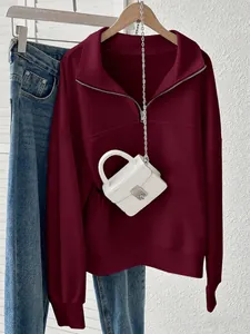 Dettaglio felpa bordeaux con mezza zip abbinata a una mini borsa bianca con effetto coccodrillo