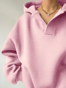 Detailansicht des V-Ausschnitts und der weichen Stofftextur eines rosa Oversize-Kapuzenpullovers.
