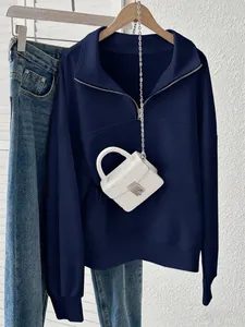 Dettaglio felpa blu navy con mezza zip e mini borsa bianca con trama a coccodrillo