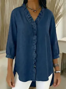 Detailed view of women's denim-look V-neck blouse featuring elegant ruffle trim