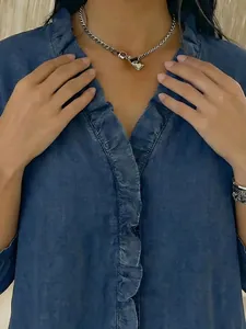 Detailed view of women's casual imitation denim V-neck shirt featuring ruffled edges.
