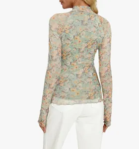 Vista trasera de un top de malla floral de manga larga con prácticos agujeros para el pulgar