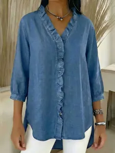 Detail view of a blue faux denim blouse featuring delicate ruffle trim and a V-neckline