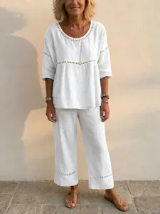 Women's white two-piece linen set with eyelet lace details and loose wide-leg trousers