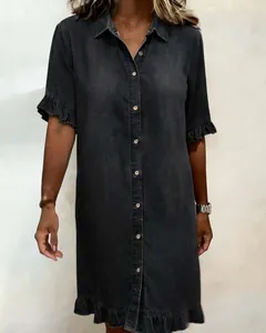 Detailed view of charcoal grey denim shirt dress with ruffle trim and button front.