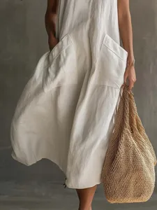 Détail d'une robe midi vintage blanche avec poches plaquées et sac en paille tressée.
