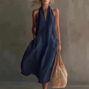 Vue de face d'une robe midi licou bleu marine avec de grandes poches et sac en paille