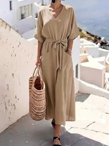 Detail of a casual khaki short-sleeved maxi dress with a waist tie in a resort setting