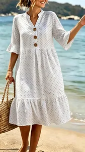 White polka dot midi dress with V-neck, button front and ruffle sleeves on beach.