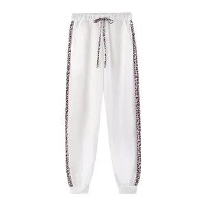 Dettaglio dei jogger bianchi con strisce laterali leopardate e coulisse coordinata.