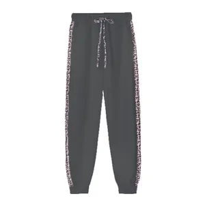 Dettaglio dei pantaloni sportivi grigi con strisce leopardate e coulisse in vita
