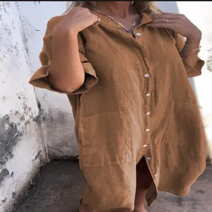 Detail view of a loose ochre linen shirt dress with pockets and buttons