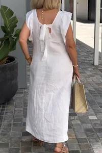 Back view of a white cotton linen dress with fly sleeves and bow tie detail