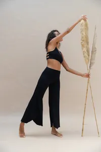Full body view of model wearing black high-waisted wide-leg yoga pants with irregular hem