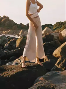 High-waisted wide-leg yoga pants for women, stylish cream casual trousers on rocky beach.