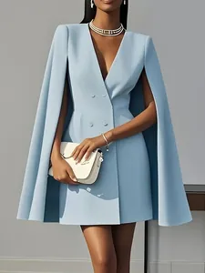 Detailed shot of a light blue double-breasted cape blazer dress worn by a model with a clutch.