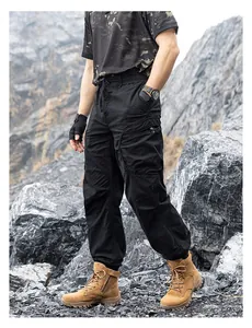 Detailed look of men's loose black techwear cargo pants with multiple pockets outdoors
