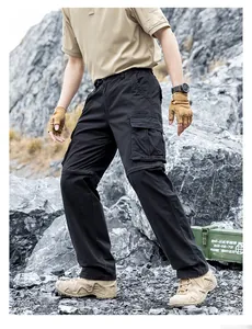 Detailed view of men's black functional cargo pants worn in a rugged mountain setting