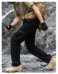 Detailed side view of black tactical cargo pants with multi-pockets in rugged terrain