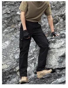 Macro view of black tactical cargo pants with multiple functional pockets on rocky terrain