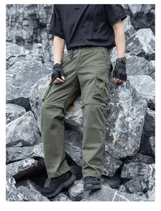 Detailed view of men's olive green multi-pocket cargo pants in a rugged outdoor setting