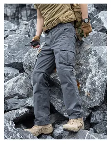 Detail view of grey functional cargo pants with multiple side pockets in an outdoor setting