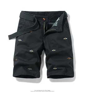 Detail shot of black cargo shorts featuring delicate embroidered bee patterns and belt