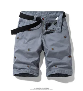 Close-up detail of vintage grey men's cargo shorts featuring bee embroidery and black belt