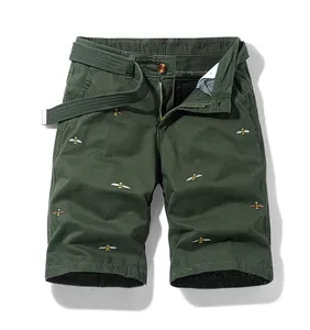 Detailed view of dark green cargo shorts featuring intricate bee embroidery and belt.