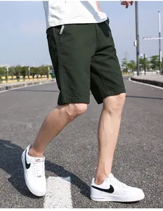 Dettaglio dei pantaloncini cargo leggeri da uomo in verde scuro indossati all'aperto