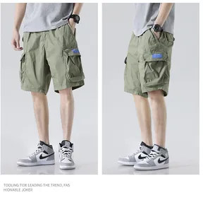 Detailed view of men's loose olive green multi-pocket cargo shorts with a casual grey tee.