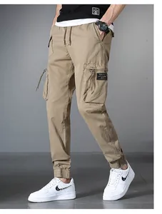 Detail view of men's khaki cargo pants with multiple utility pockets and elastic cuffs