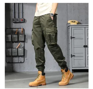 Vue complète du pantalon cargo jogger homme vert olive dans un décor industriel