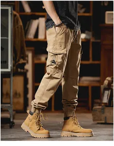 Detailed side view of men's khaki multi-pocket cargo pants with cuffed hems and boots.