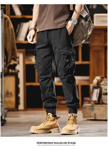 Full-length view of men's black multi-pocket jogger cargo pants in a studio setting
