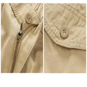 Close-up details of zipper and button pocket on khaki cotton cargo shorts.