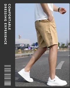 Side view of a man walking outdoors wearing khaki summer cargo shorts and white sneakers
