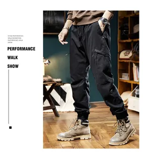 Detailed view of men's black outdoor cargo jogger pants styled with work boots in studio