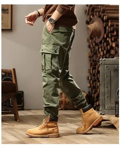 Detail of men's army green cargo jogger pants worn by a model in a rustic industrial setting.