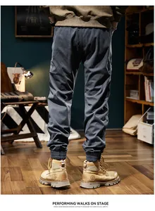 Back view of men's dark gray cargo jogger pants styled with work boots in a studio.