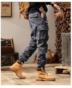 Detail view of men's grey retro multi-pocket cargo pants with tapered beam foot design.