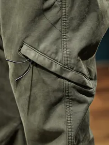 Close-up of olive green outdoor cargo pants featuring a unique drawstring pocket design
