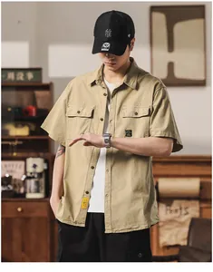 Man in a khaki short-sleeved cargo shirt with dual chest pockets in a retro setting.