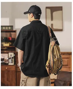 Back view of a men's retro black short-sleeved cargo shirt in a vintage indoor setting.